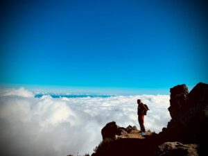 René Fritzsche auf einem Berggipfel über einem Wolkenmeer – Die Stille der Natur inspiriert den Energieberater zu nachhaltigen Lösungen für kommende Generationen.