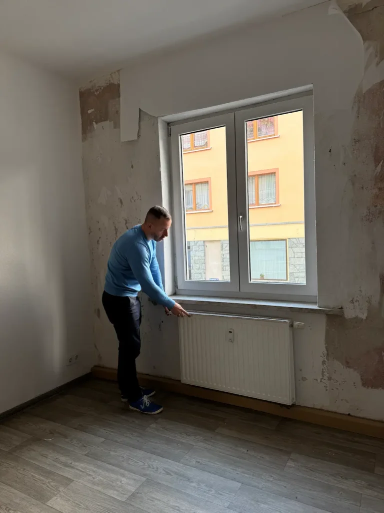 Zertifizierter Energieberater inspiziert Fenster und Heizung zur Erstellung eines individuellen Sanierungsfahrplans (iSFP).